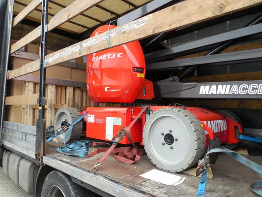 Nacelle élévatrice articulée rouge arrimée sur le plateau d'un camion